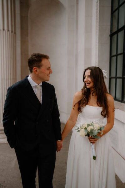 Couple holding hands in wedding attire, smiling.