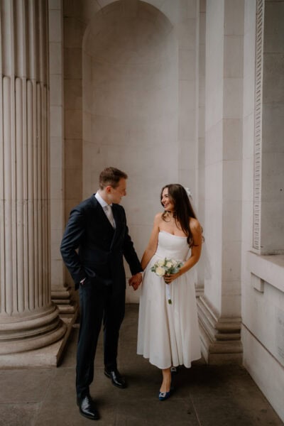 Bride and groom smiling in grand hall.