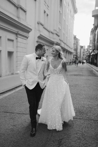 Bride and groom walking on city street
