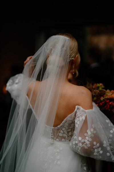 Bride in embroidered dress and veil holding bouquet