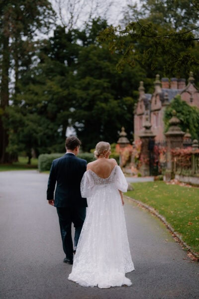 Couple walking in garden near historic building.