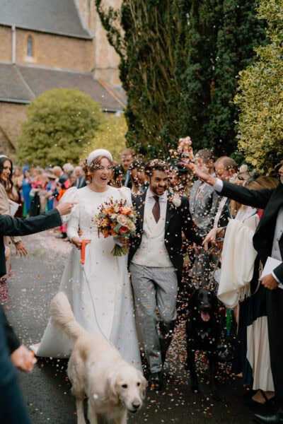 Happy wedding couple leaves church with confetti shower.