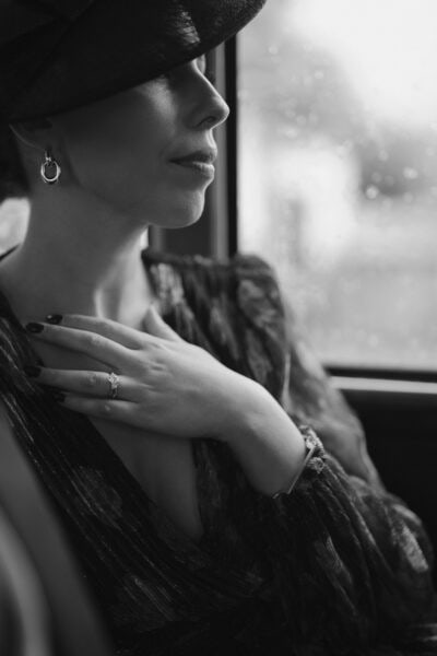 Woman in hat sitting by rainy window