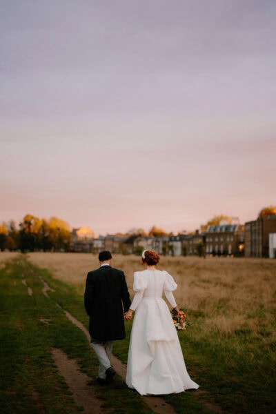 Couple walks hand-in-hand at sunset, scenic background.
