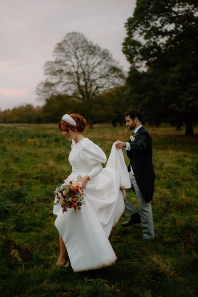 Couple walking in field during wedding ceremony.