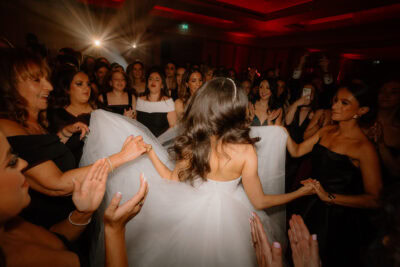 Bride dancing joyfully with guests at wedding reception.