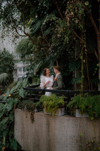 Couple smiling in lush garden setting.